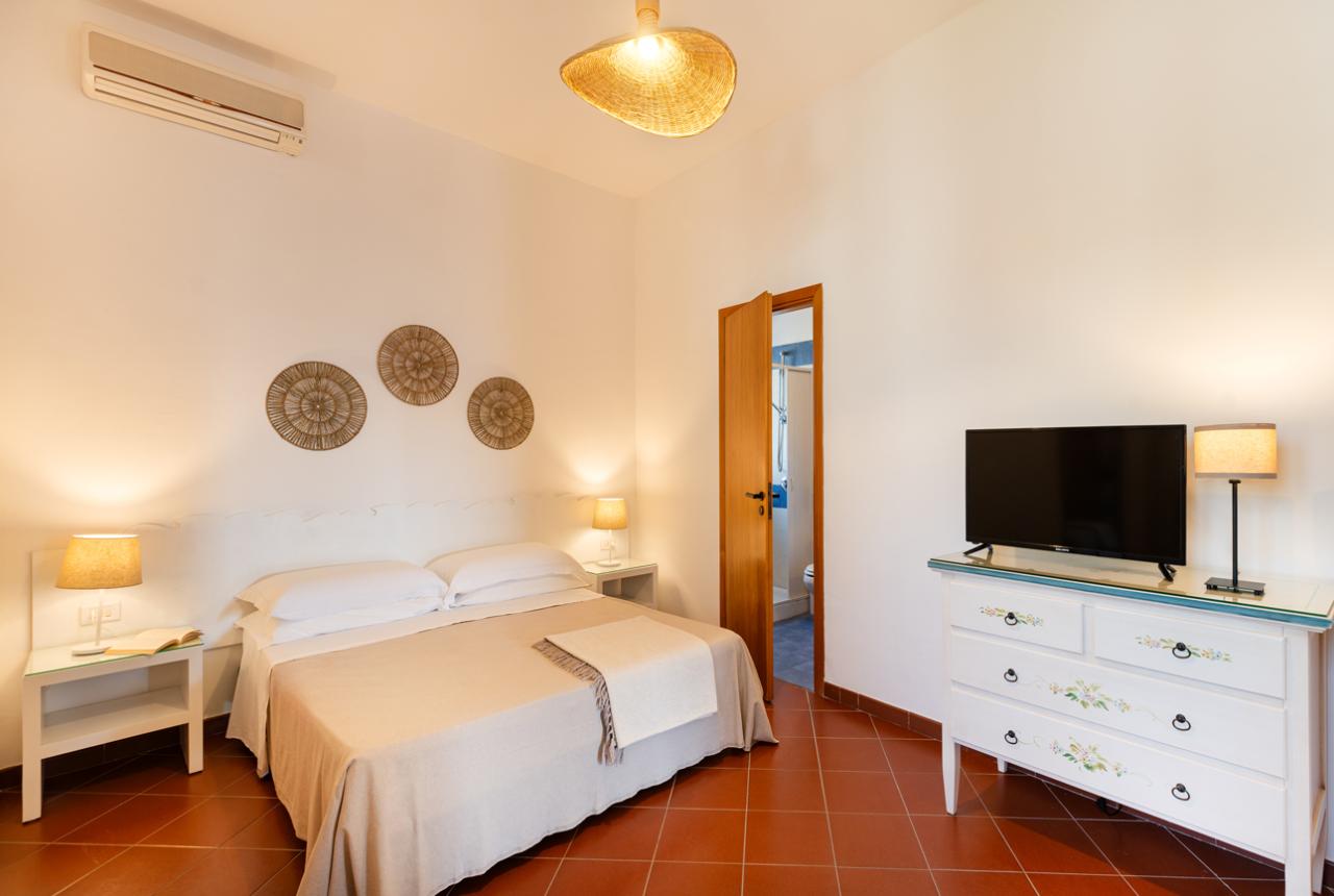 Camera accogliente con letto matrimoniale, TV e decorazioni murali.