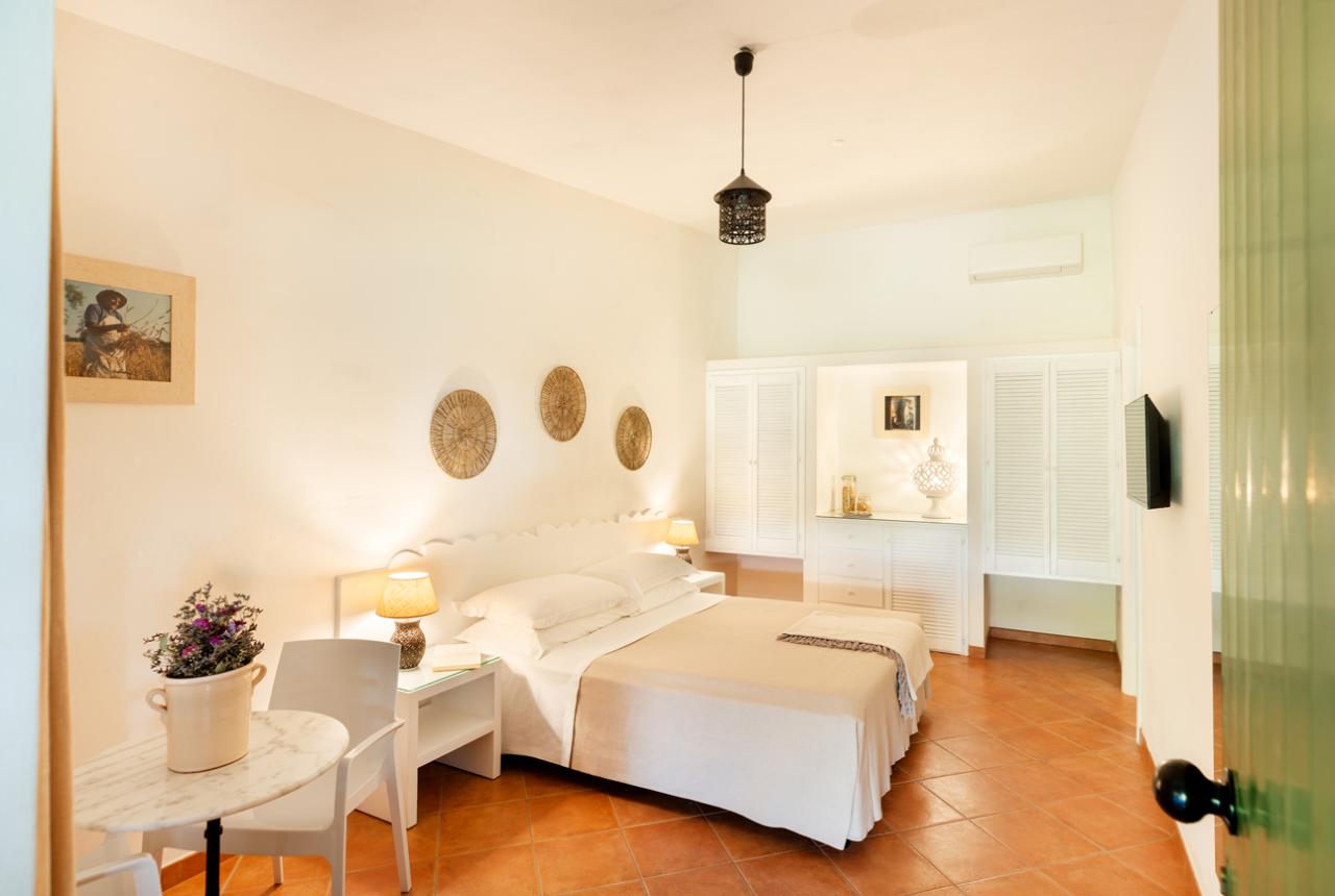 Camera da letto luminosa con arredi bianchi e decorazioni naturali.