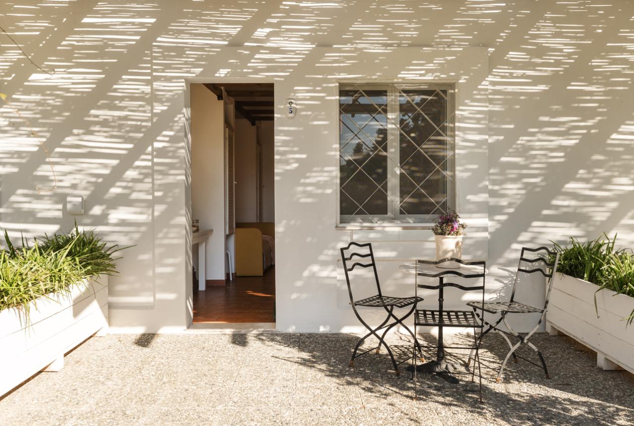 Terrazza con sedie in ferro battuto e piante, ombre a strisce.