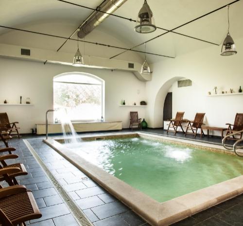 Piscina interna elegante con sedie a sdraio in legno e illuminazione moderna.