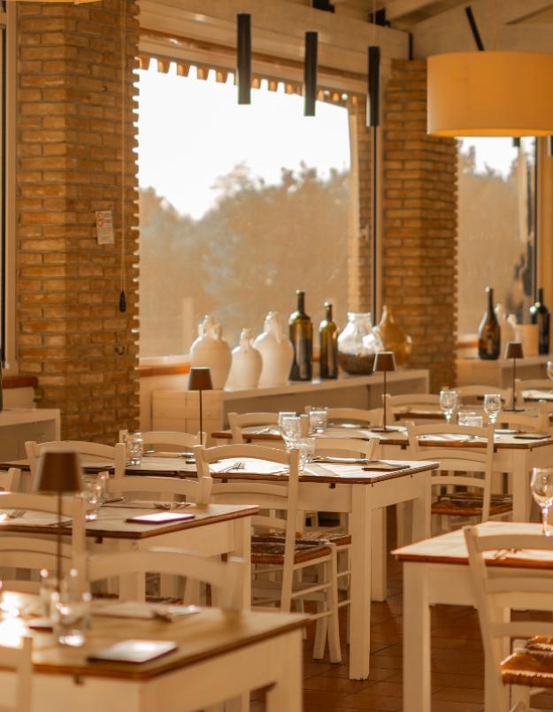 Ristorante accogliente con tavoli apparecchiati, luce calda e decorazioni in vetro.